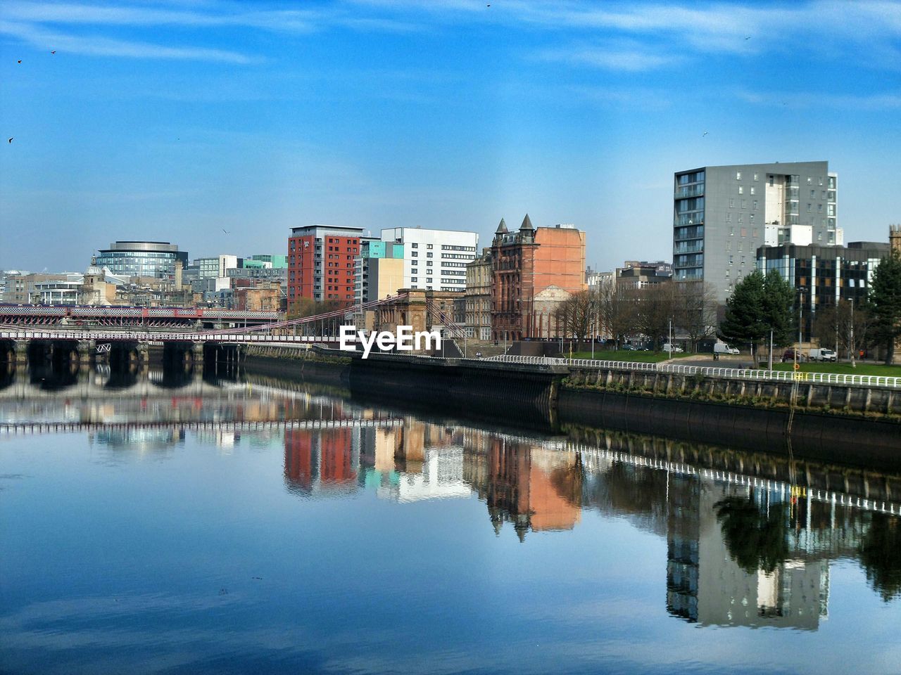 Reflection of buildings in river against blue sky