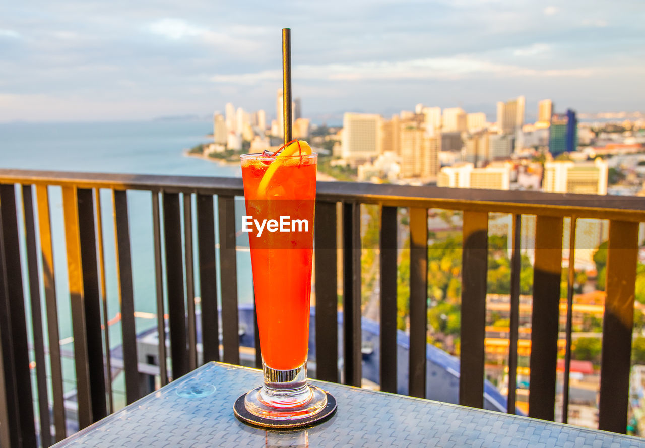 CLOSE-UP OF DRINK ON TABLE BY SEA