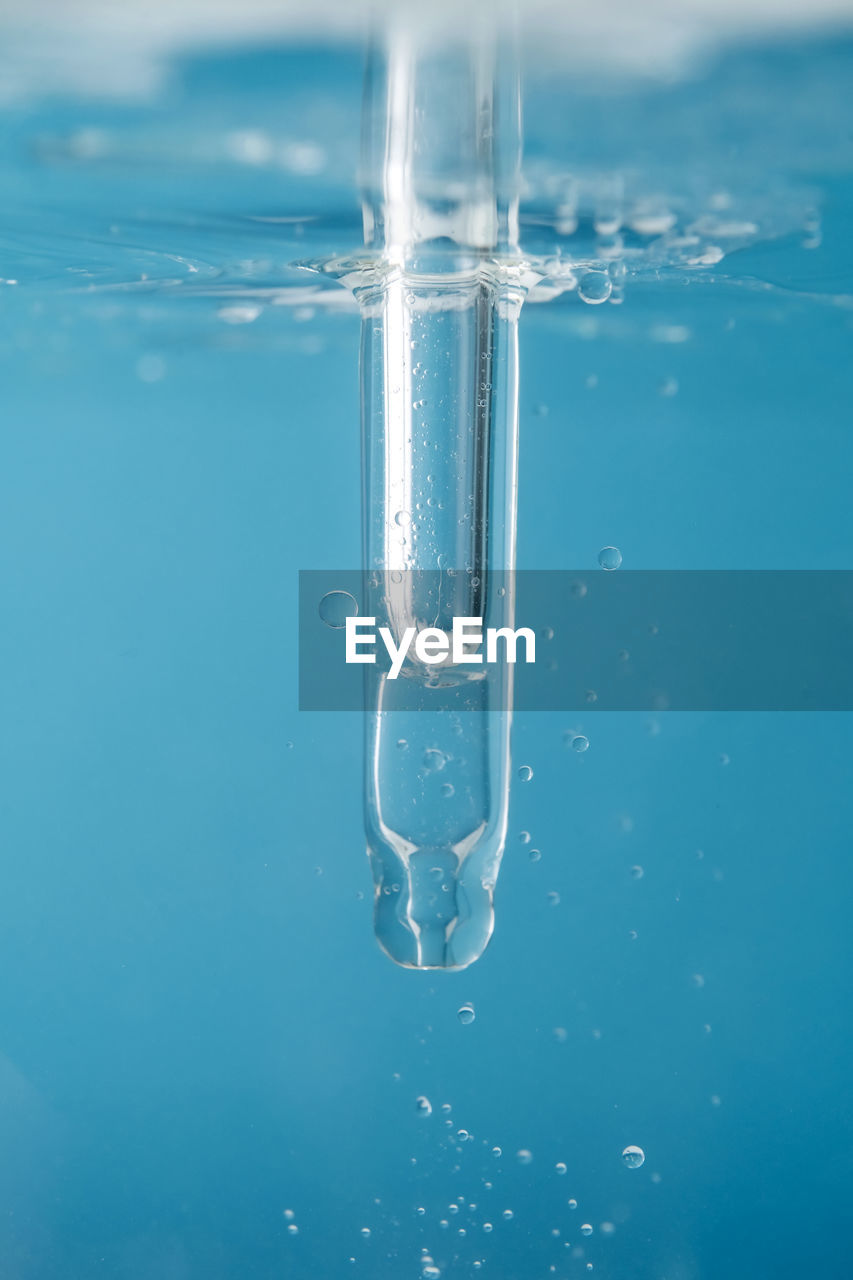 Pipette with cosmetic product in water with bubbles.