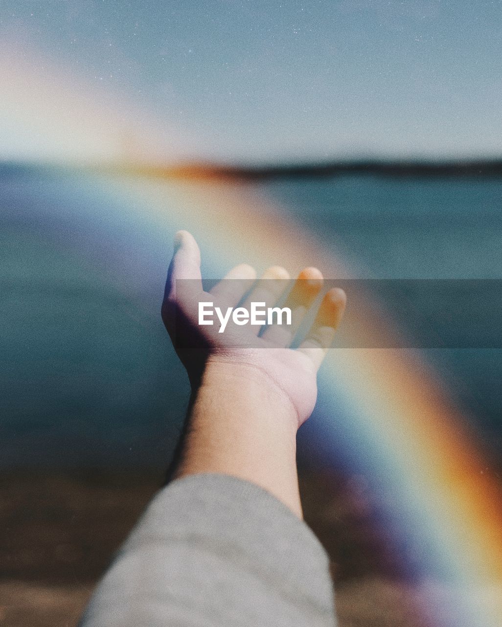 Close-up of hand against sea and sky