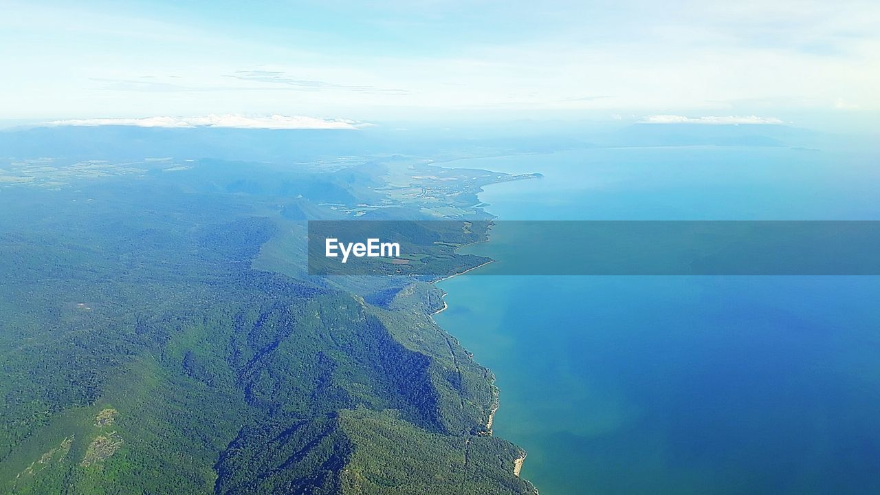 AERIAL VIEW OF SEA BY MOUNTAINS AGAINST SKY