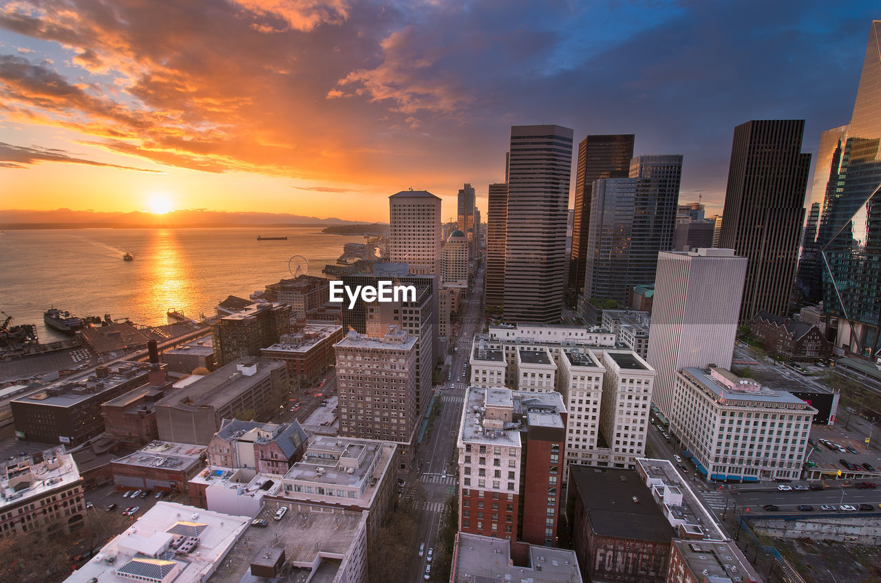 High angle view of buildings by sea against sky during sunset