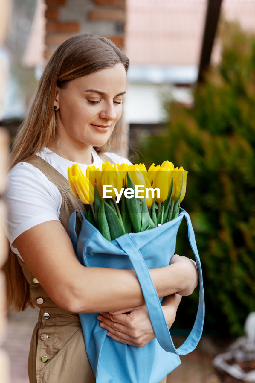 Portrait of a happy female florist with a bouquet of yellow tulips. women's day, valentine's day