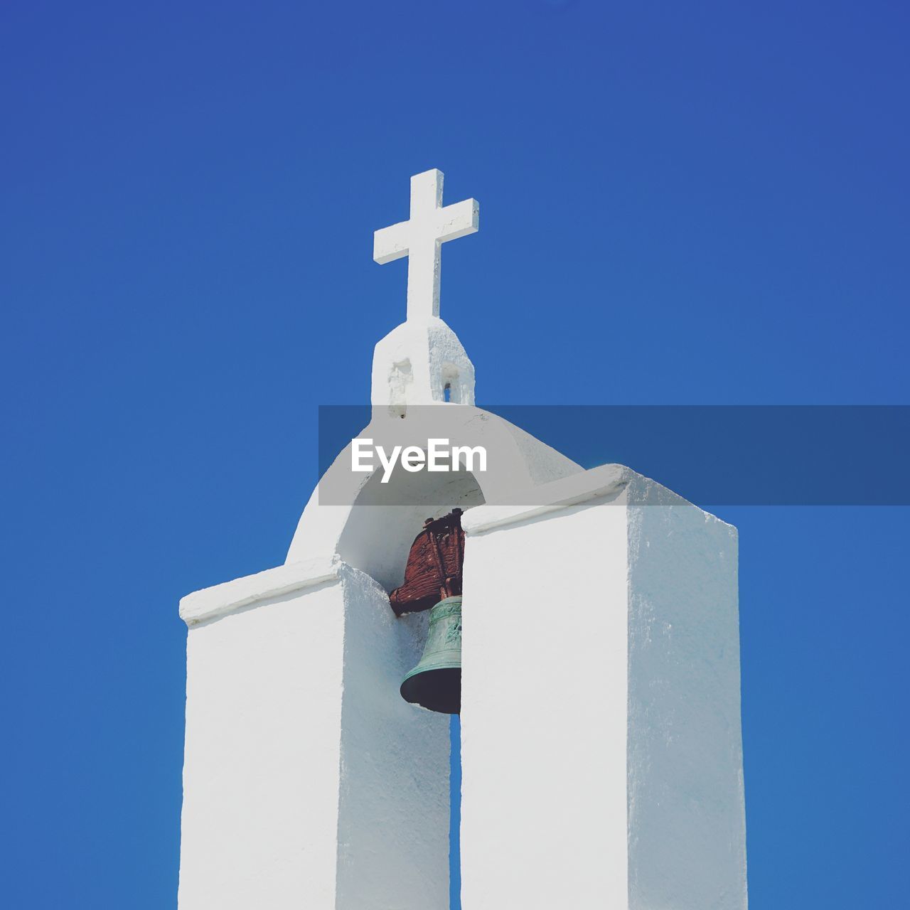 Greek church bell tower against blue sky 
