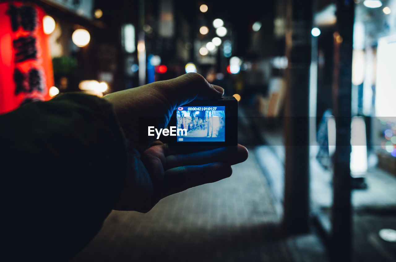 Cropped hand of person holding camera at night