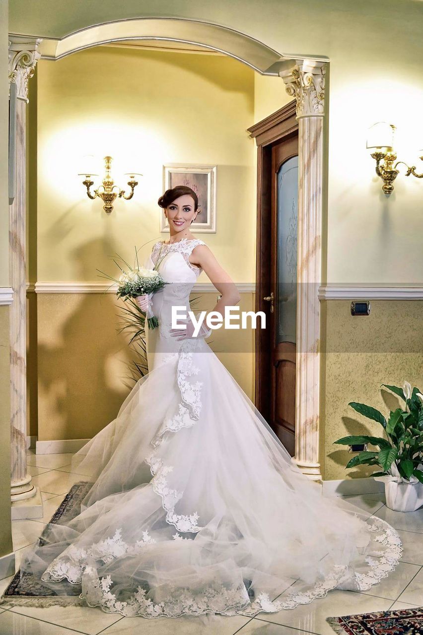 Portrait of smiling young bride with bouquet at home