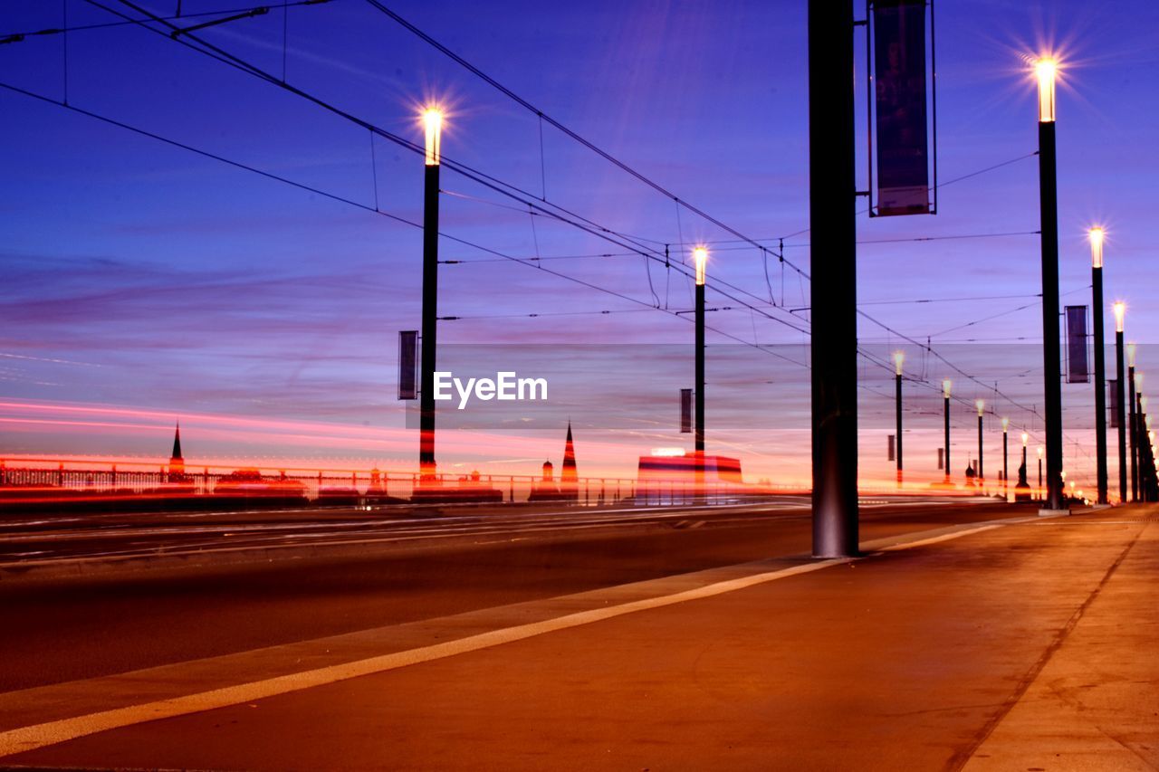 Light trails on road against sky at sunset