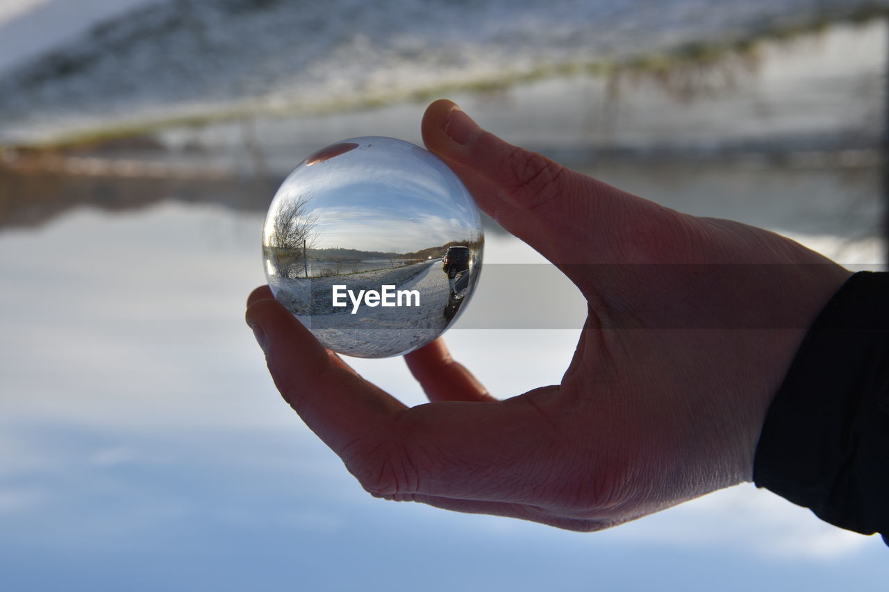 CLOSE-UP OF MAN HAND HOLDING CRYSTAL BALL