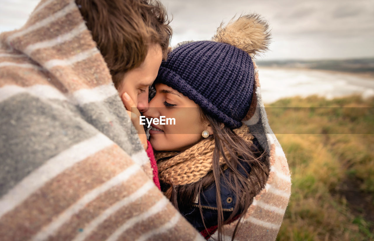 Couple covered with blanket romancing on field