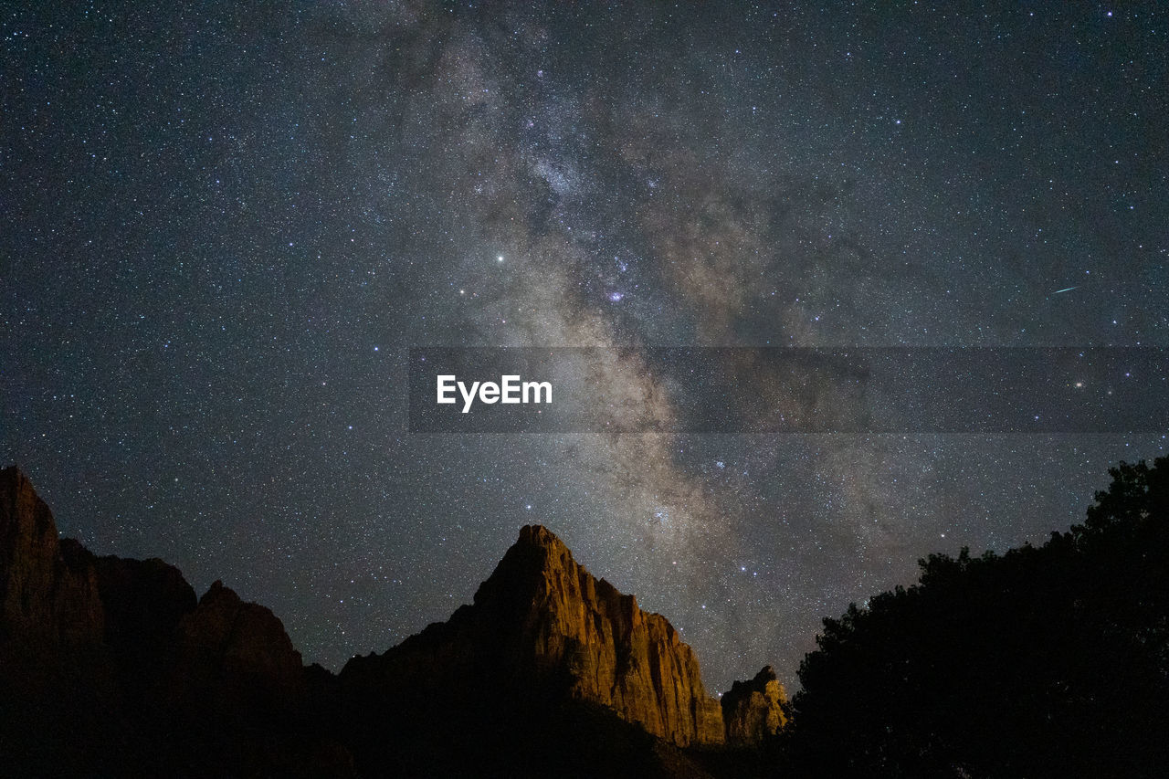 Low angle view of star field and mountains against sky at night