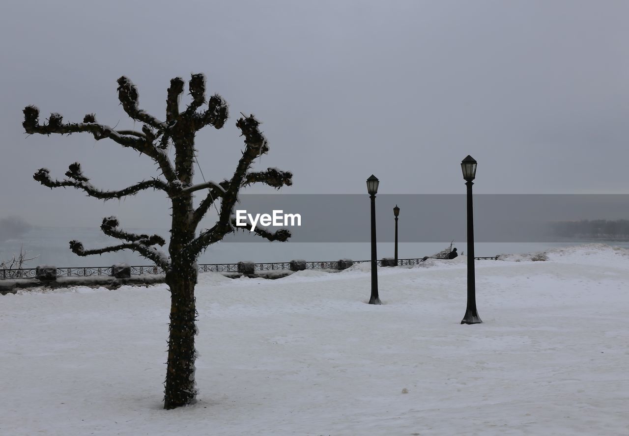 Street light on snow covered field against sky