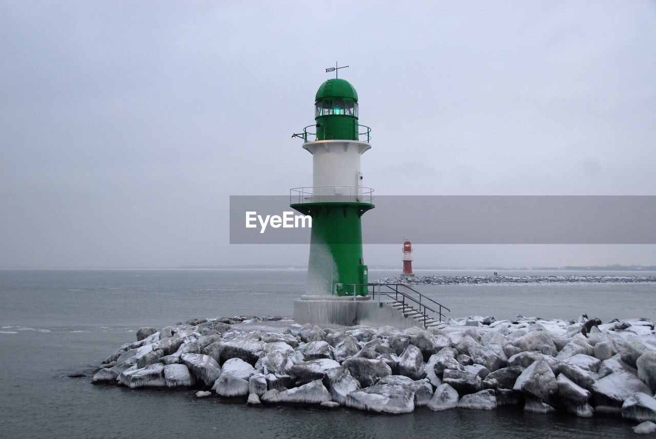 Lighthouse by sea against sky