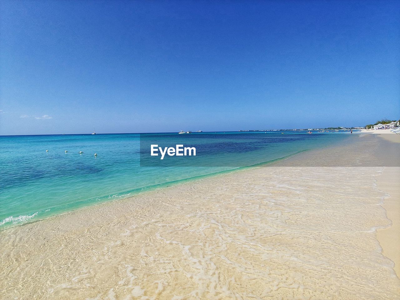 Scenic view of beach against clear blue sky