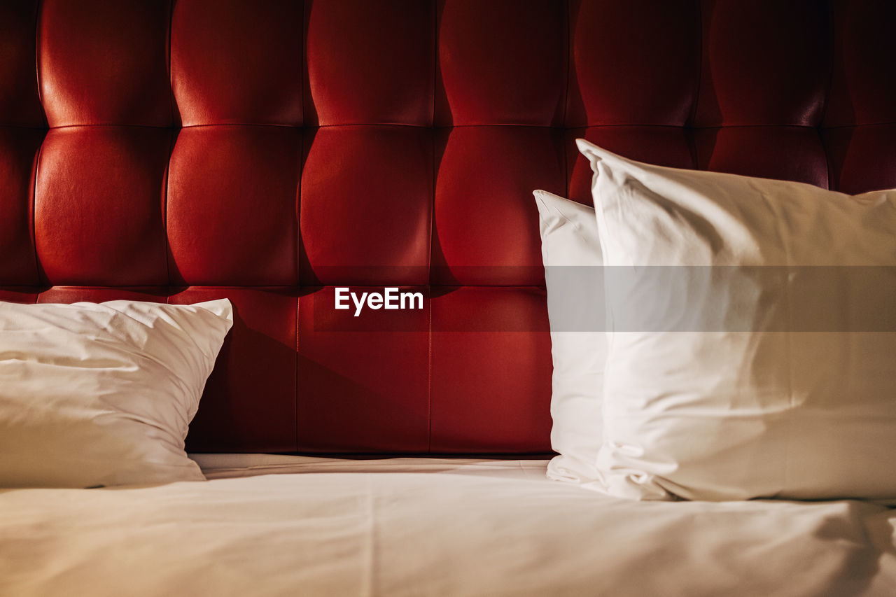 White pillows in front of red upholstered wall