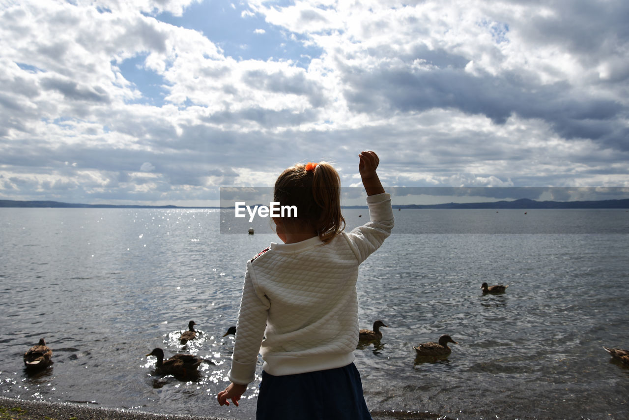 Rear view of girl standing at lakeshore