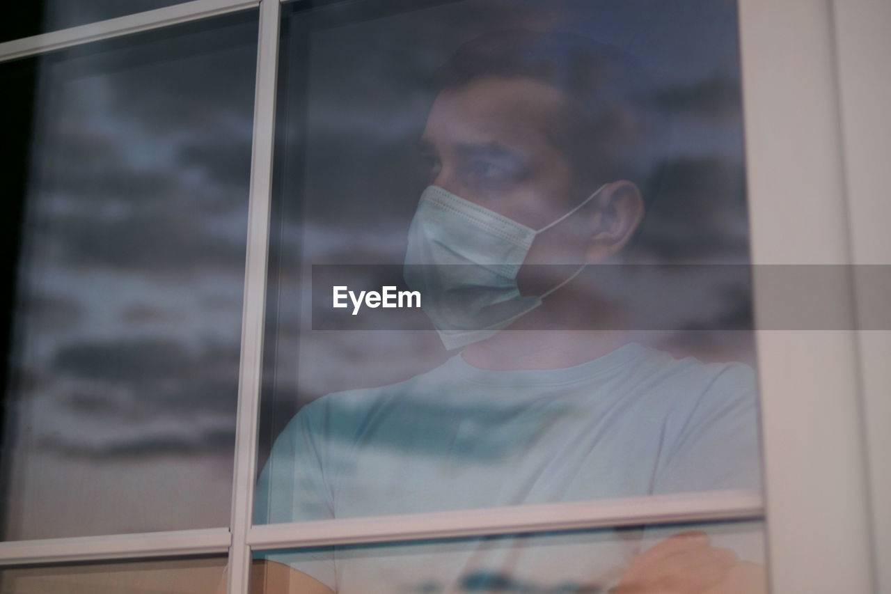 Man looking away while looking through window