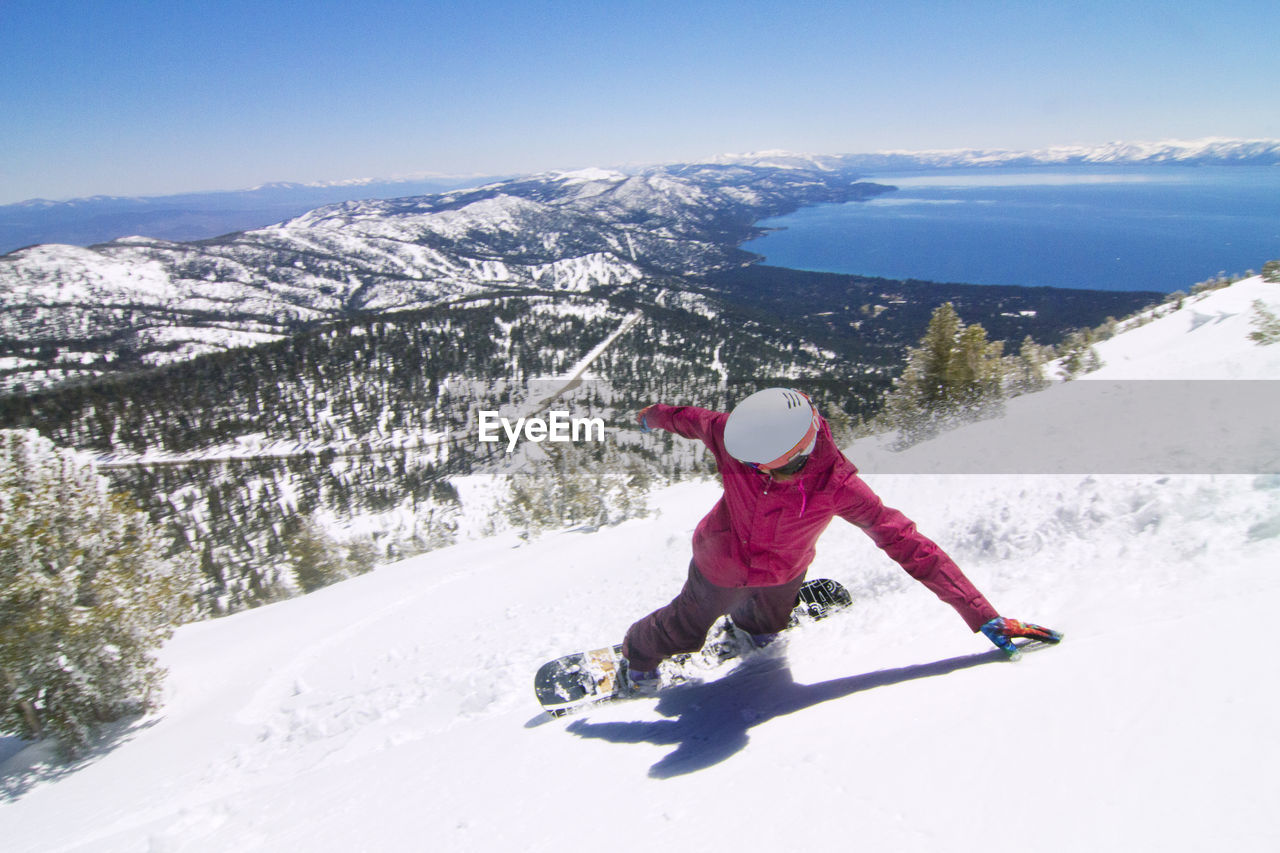 High angle view of female snowboarder descending from snowcapped mountain