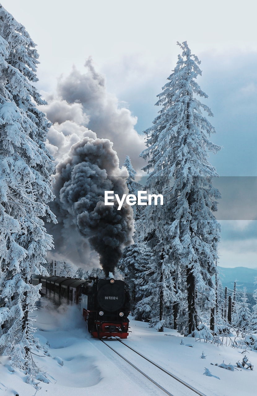 TRAIN ON RAILROAD TRACK AGAINST SNOW COVERED MOUNTAINS