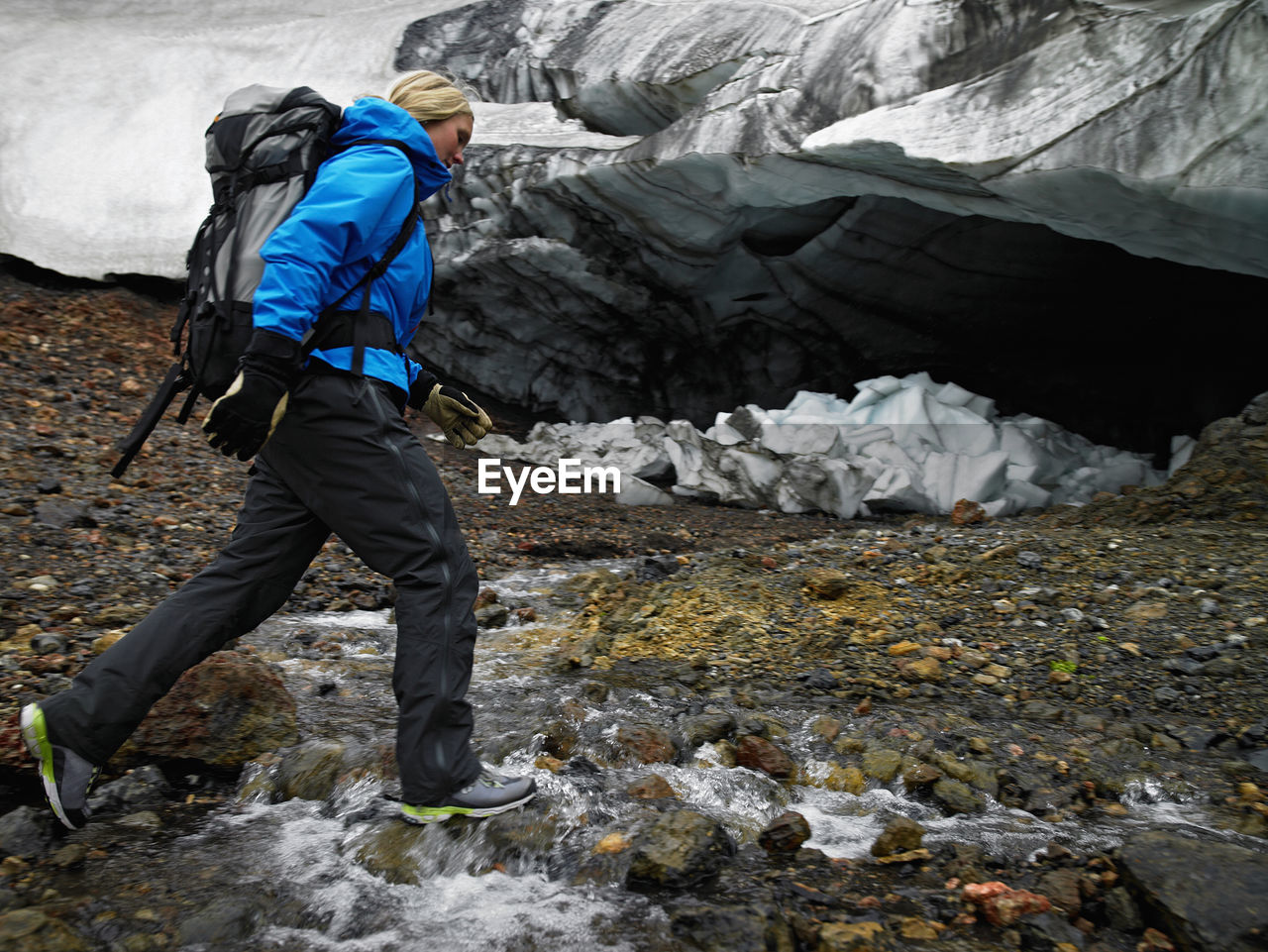 Young woman crossing river at hrafntinnusker in iceland