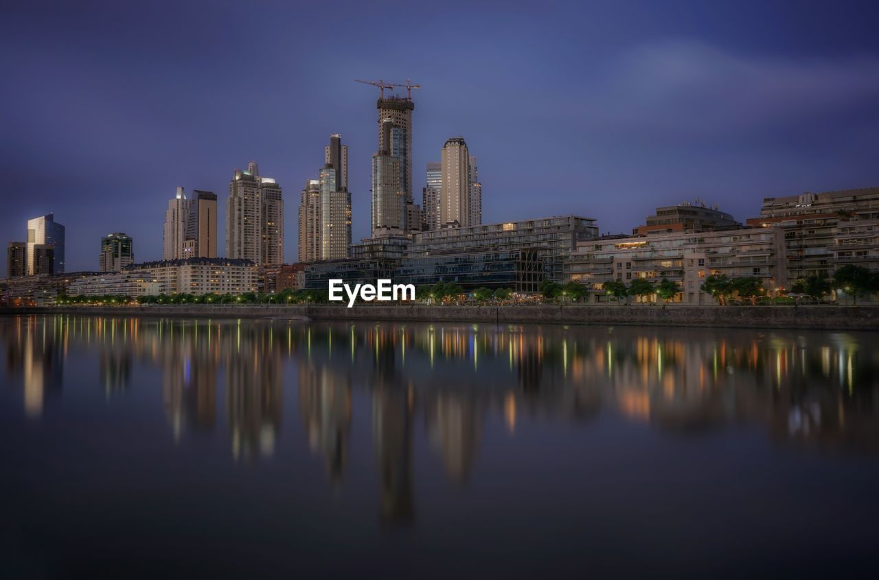 Reflection of skyscrapers in river against sky