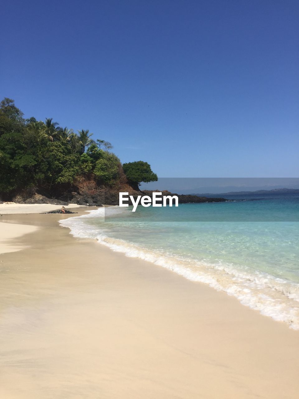 Scenic view of beach against clear blue sky