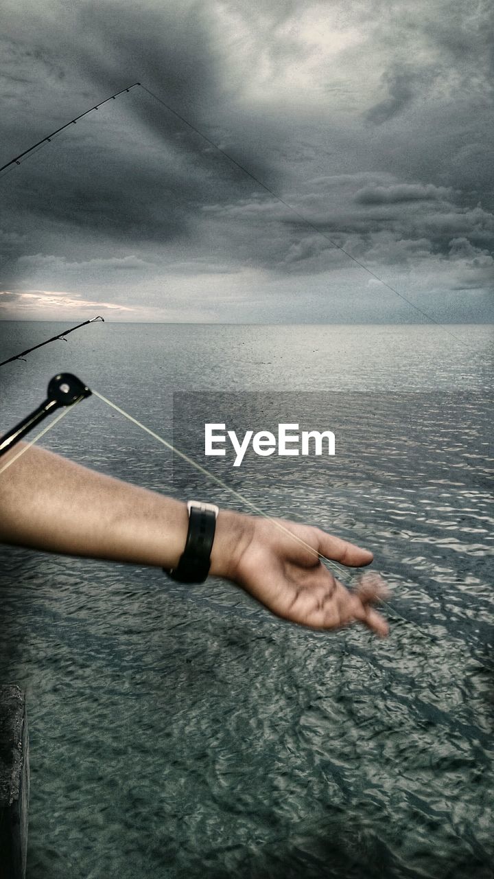 Close-up of hand sailing in sea against sky