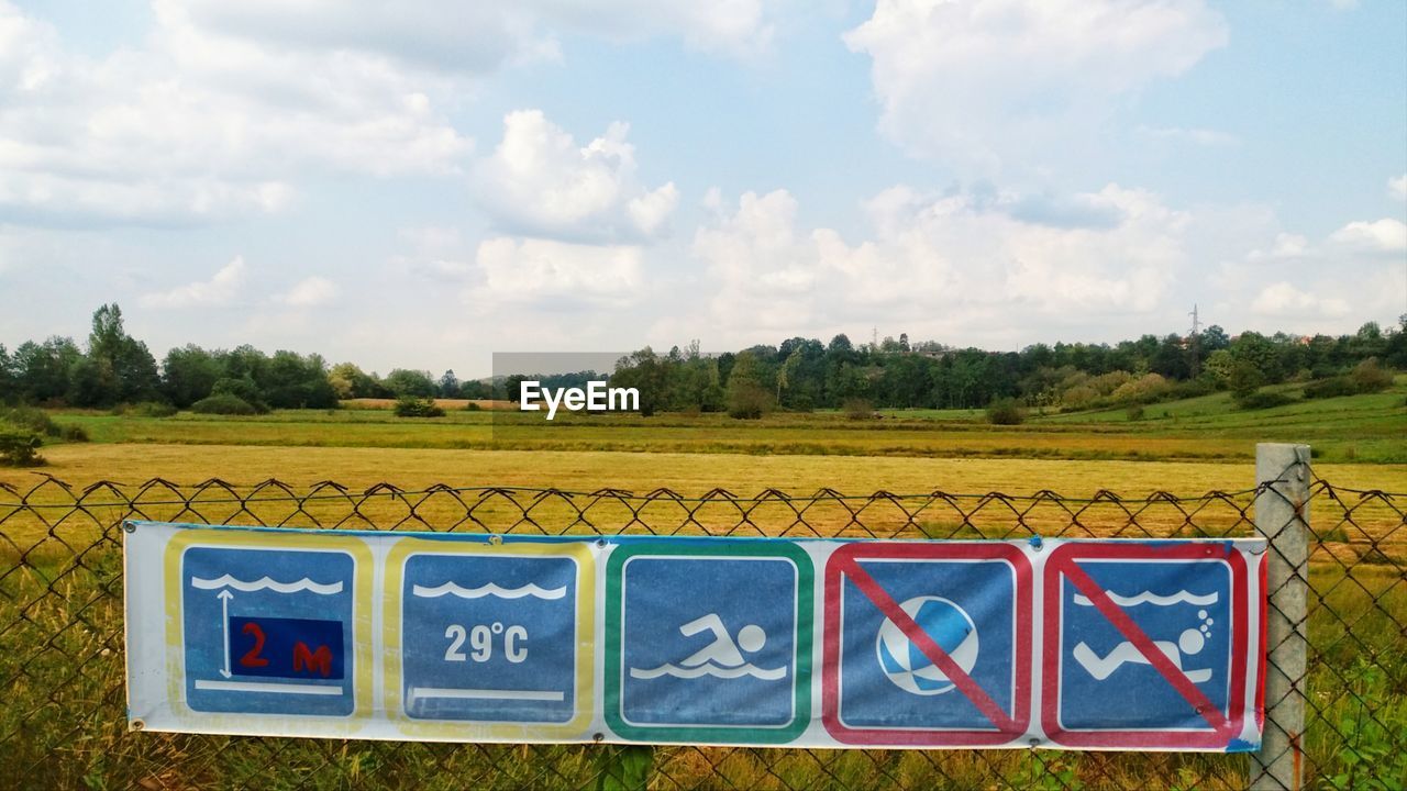 Information sign on field against sky