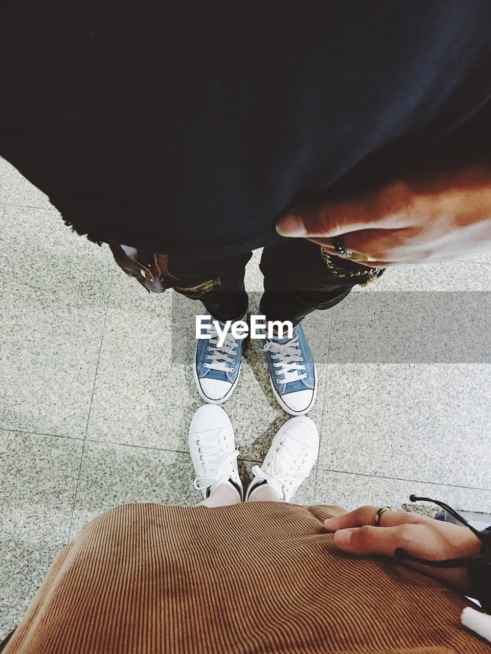 Low section of friends wearing canvas shoes on footpath