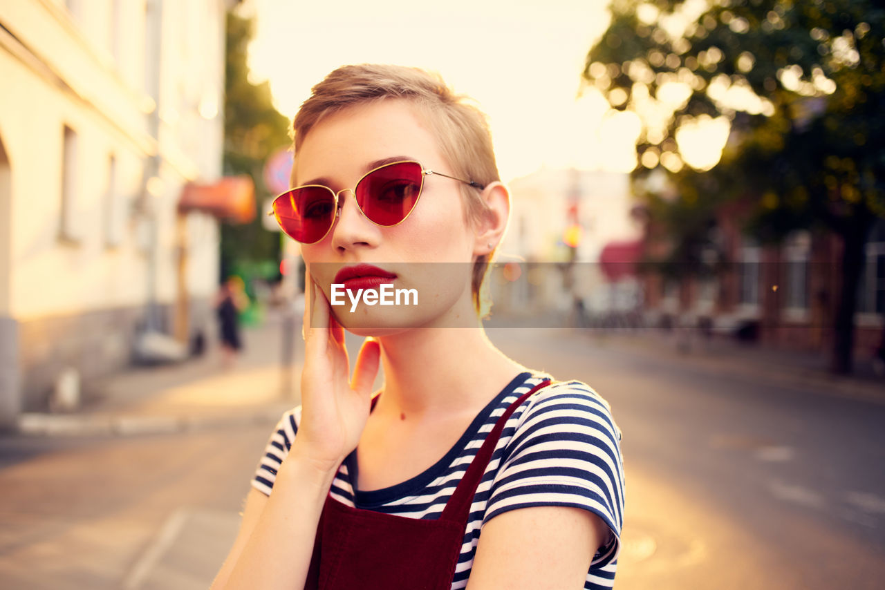 PORTRAIT OF WOMAN WEARING SUNGLASSES IN CITY