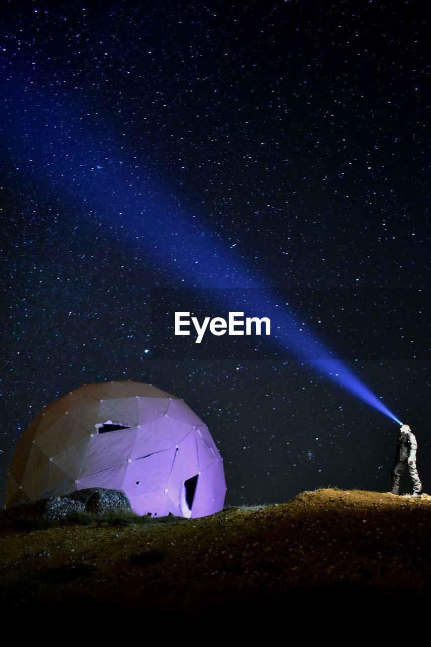 Man with illuminated headlamp standing against star field