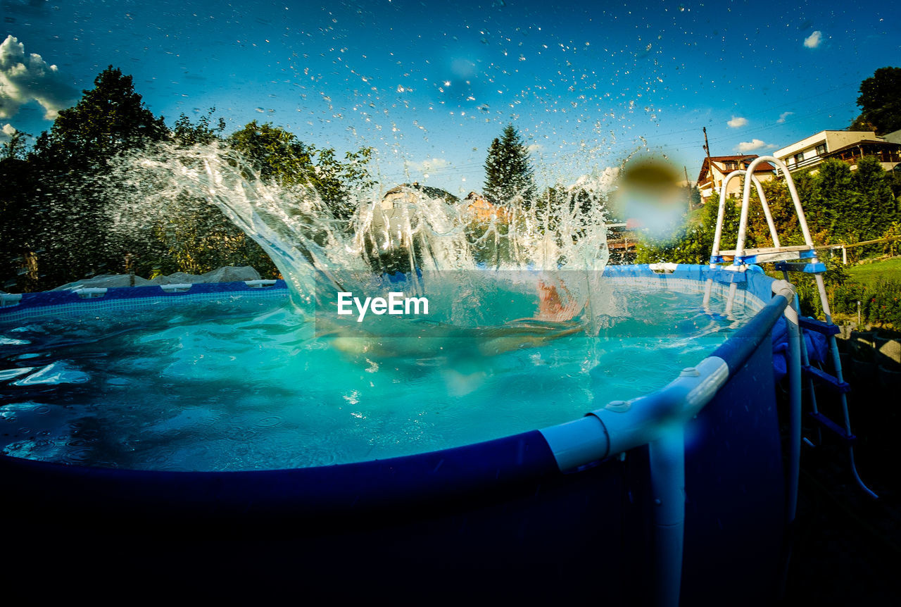 Person jumping in wading pool at yard