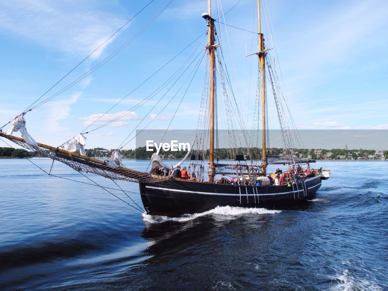 People on ship sailing on sea against sky