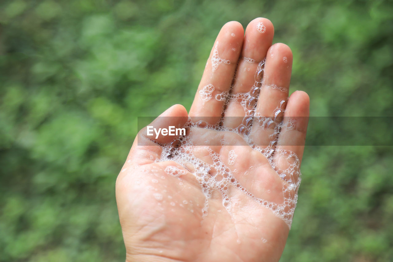 CLOSE-UP OF PERSON HAND HOLDING WET OUTDOORS