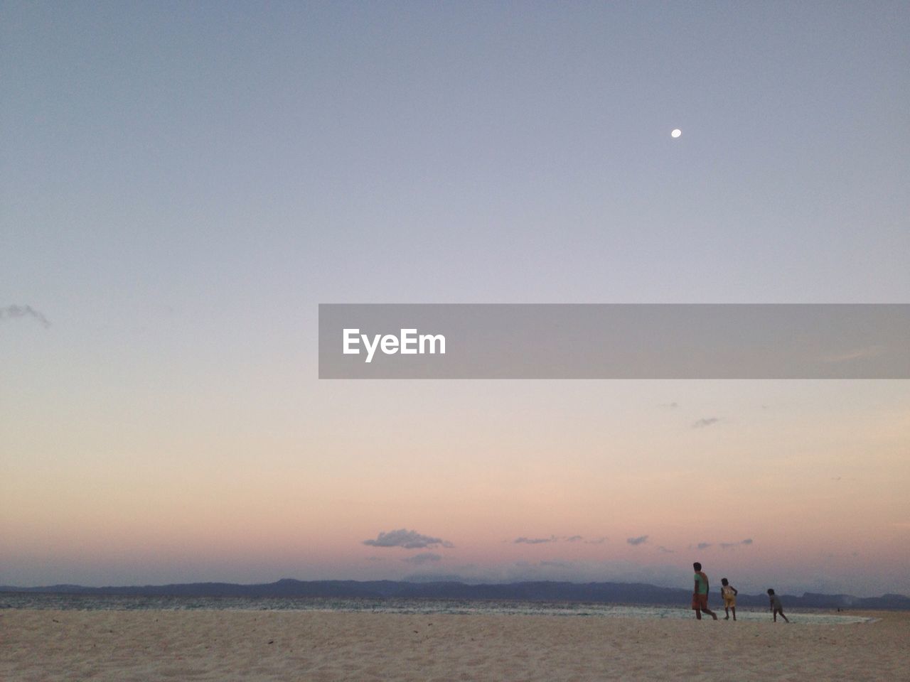 Father with son at beach against sky during sunset