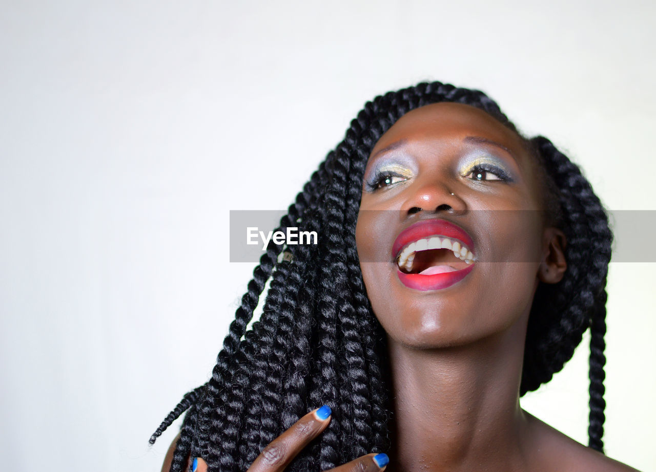 Close-up of woman with make-up against white background