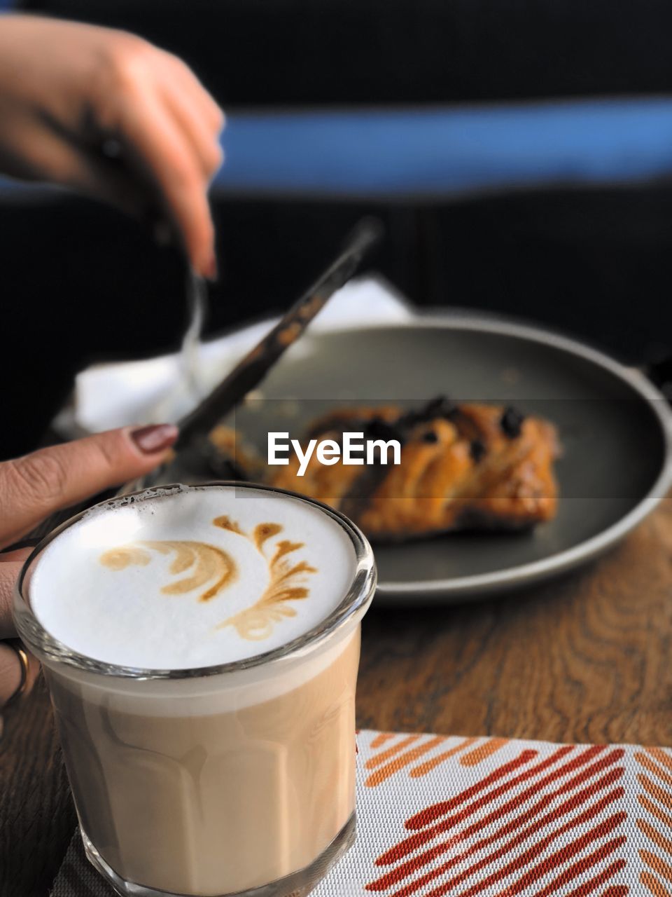 Cropped hands of woman having food and coffee on table