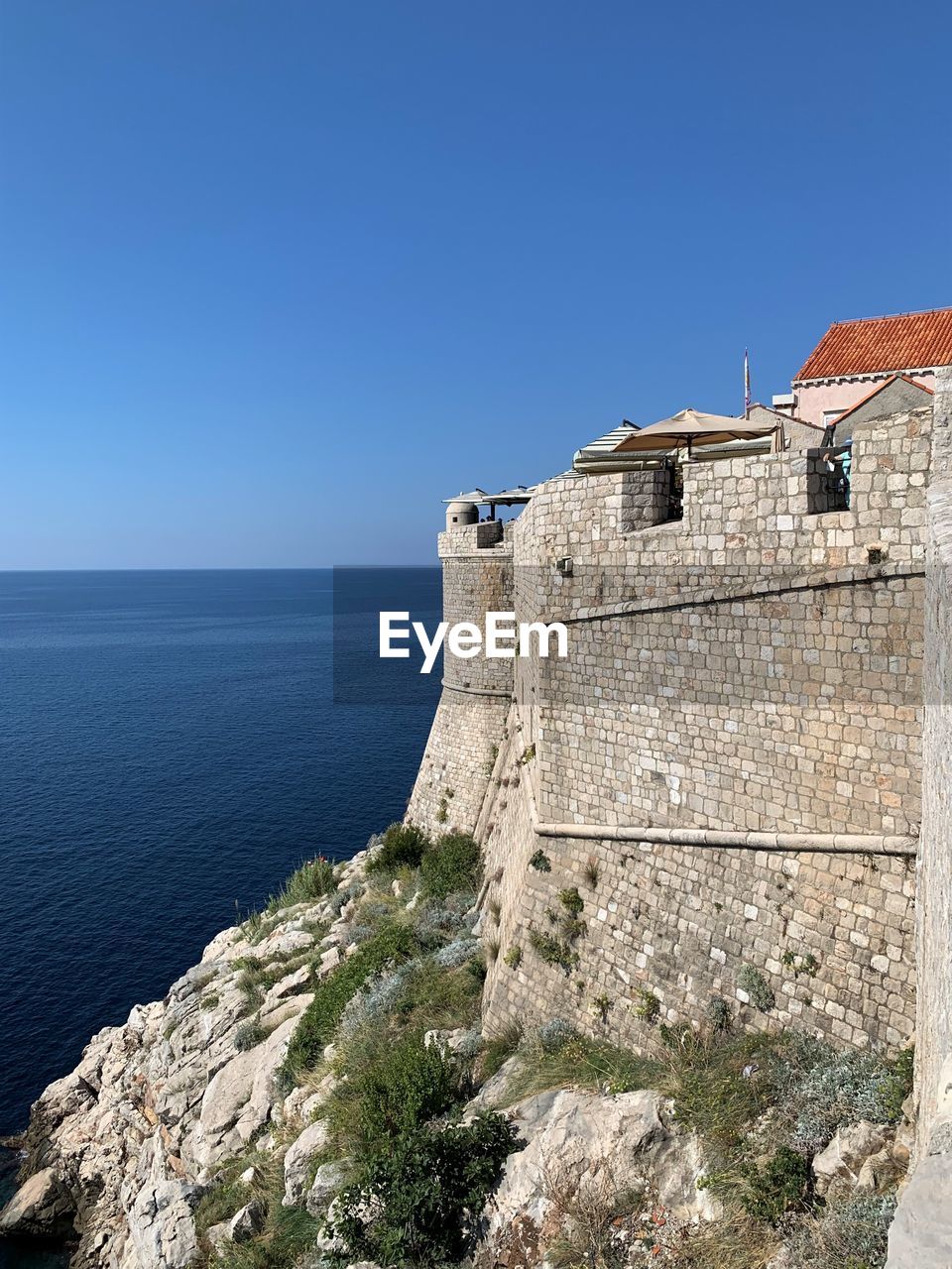 Building by sea against clear blue sky