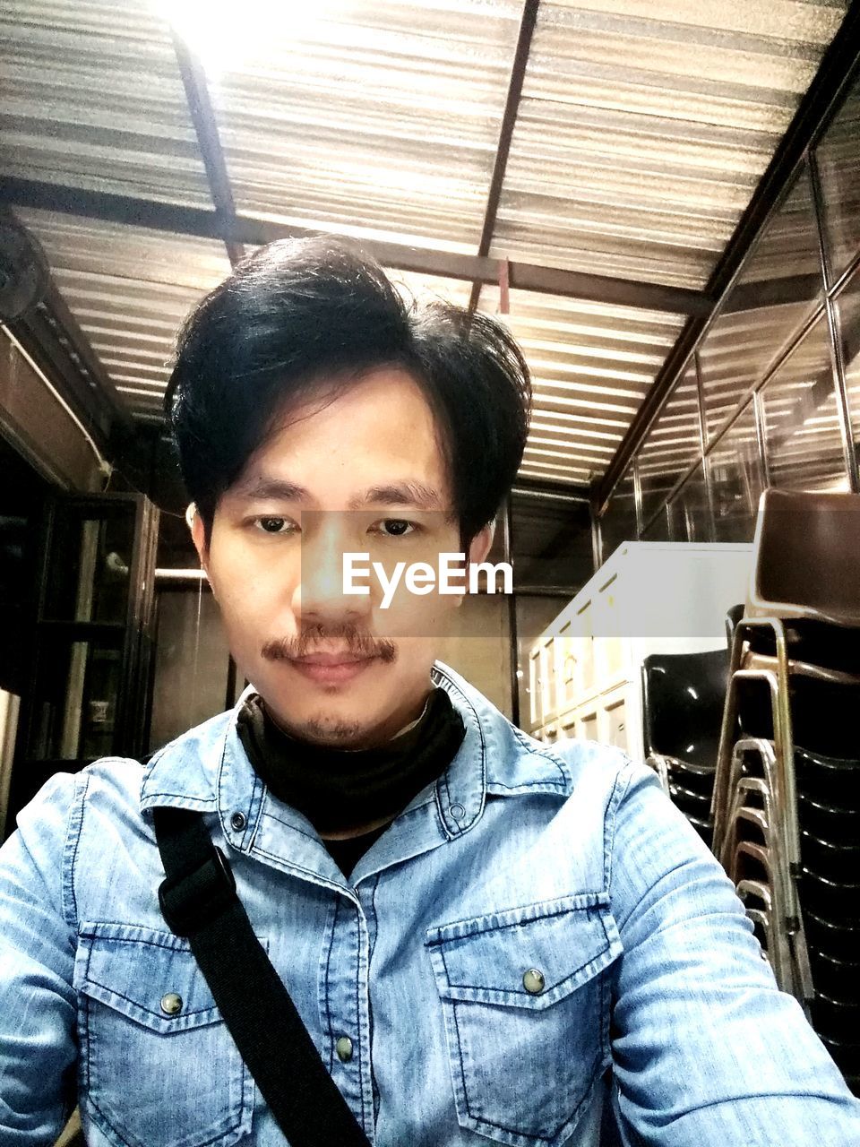 PORTRAIT OF YOUNG MAN STANDING IN SHOPPING MALL