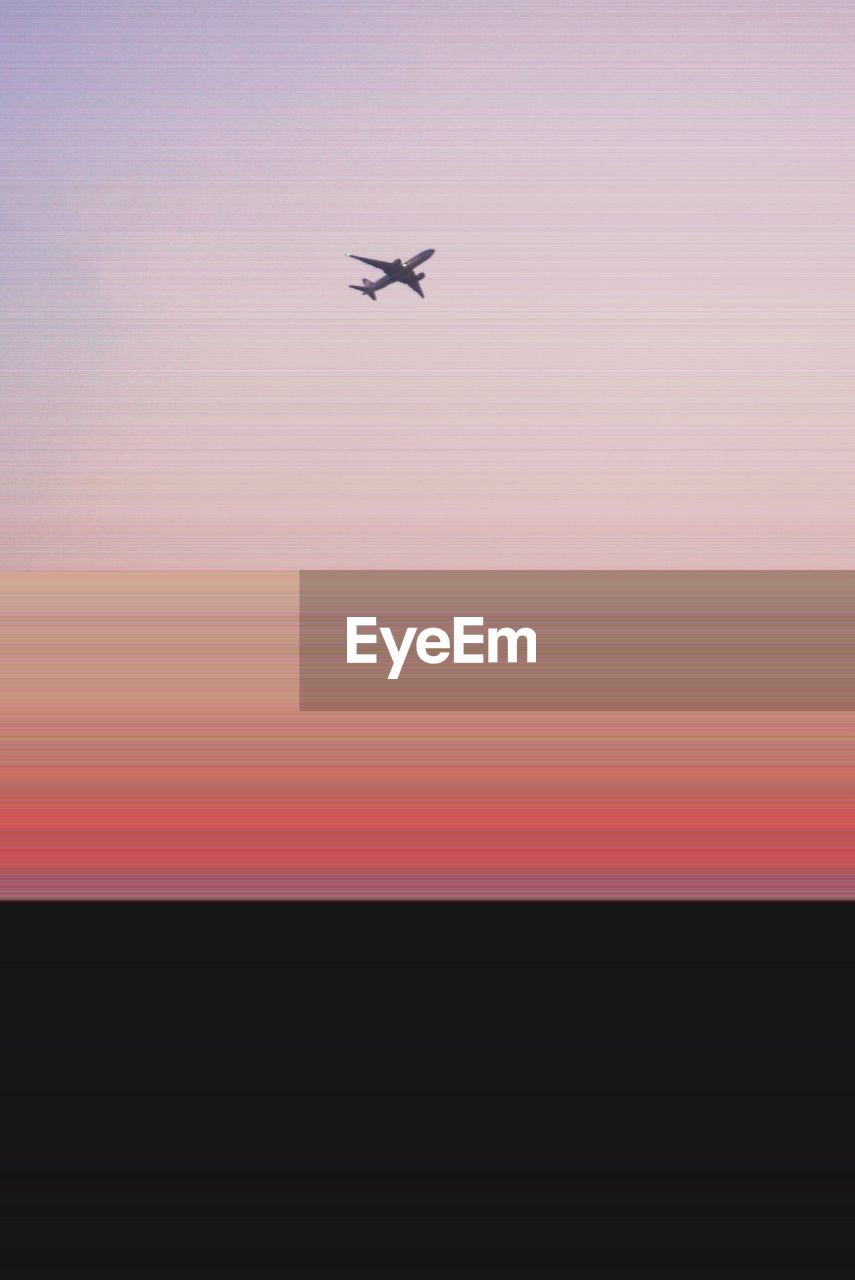 Low angle view of airplane against sky during sunset