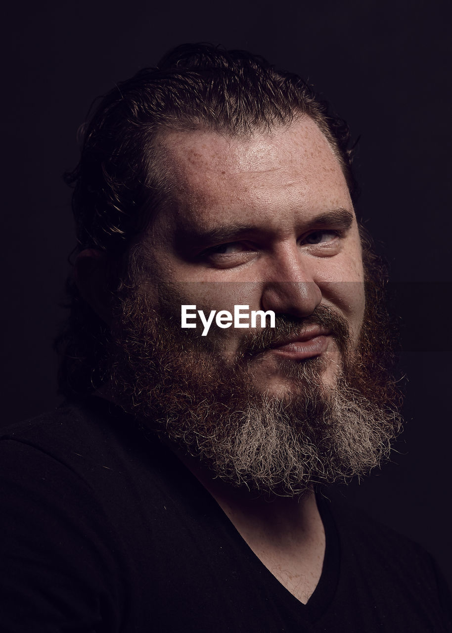 Close-up of bearded man against black background