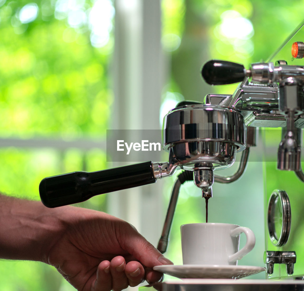 CLOSE-UP OF HAND HOLDING COFFEE CUP AGAINST BUILDING