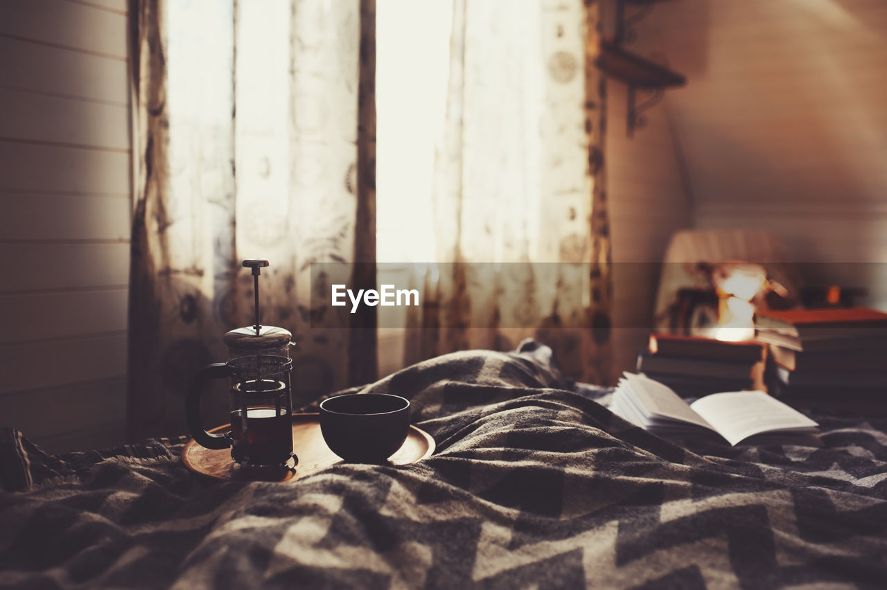 Coffee pot and cup on bed at home