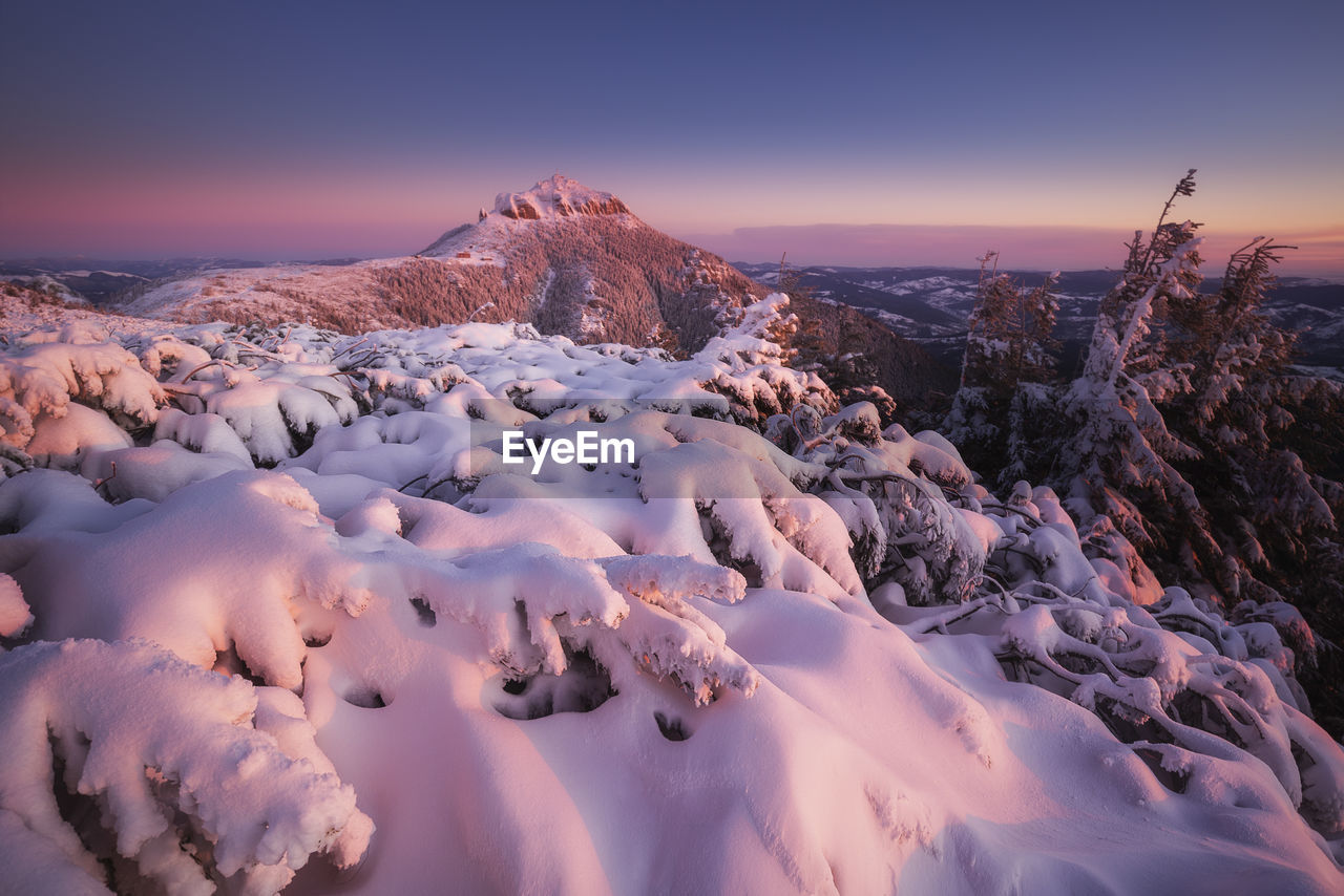 Snow covered landscape against sky during sunset in ceahlau mountains 