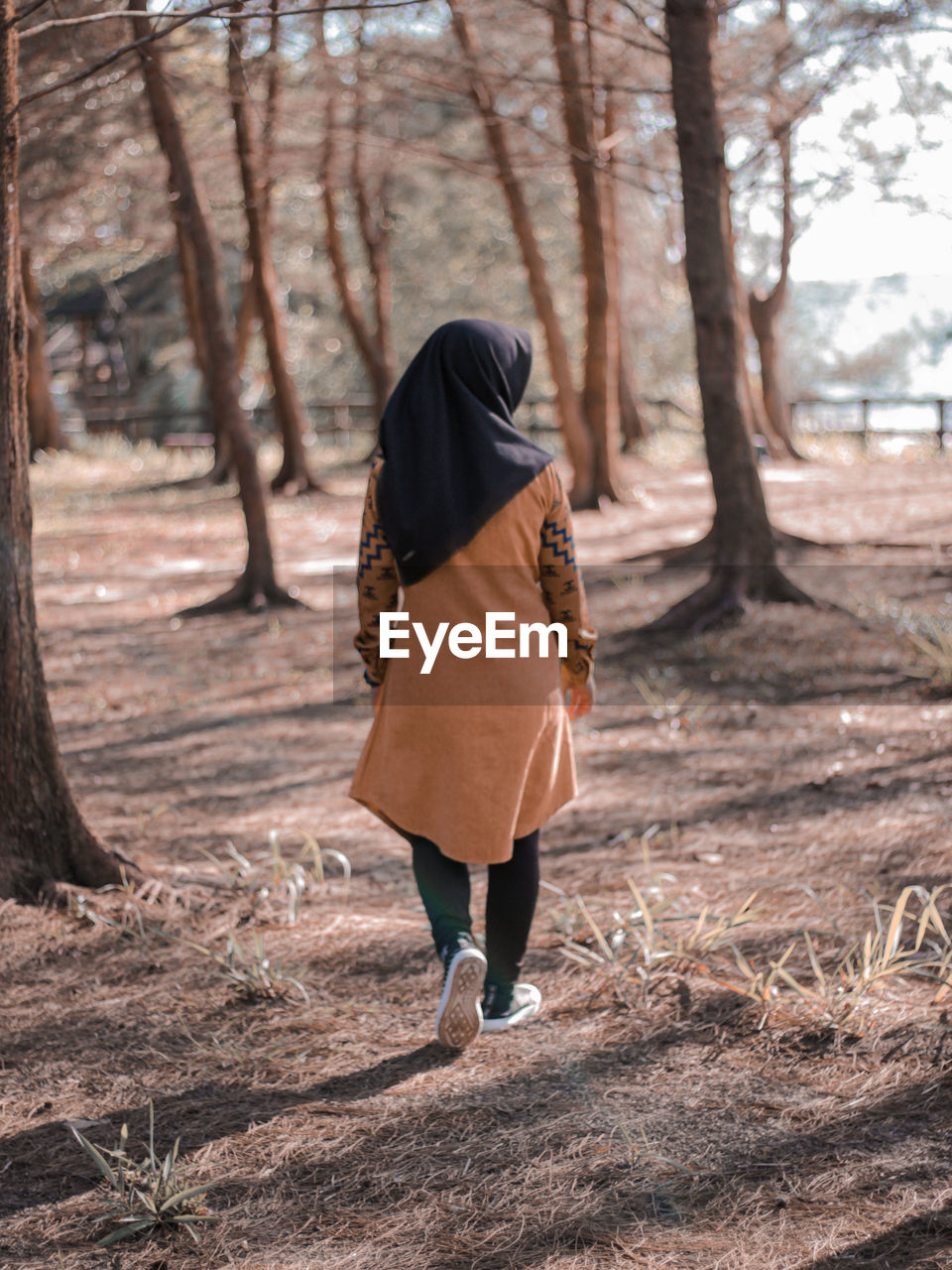 Rear view of woman walking on field