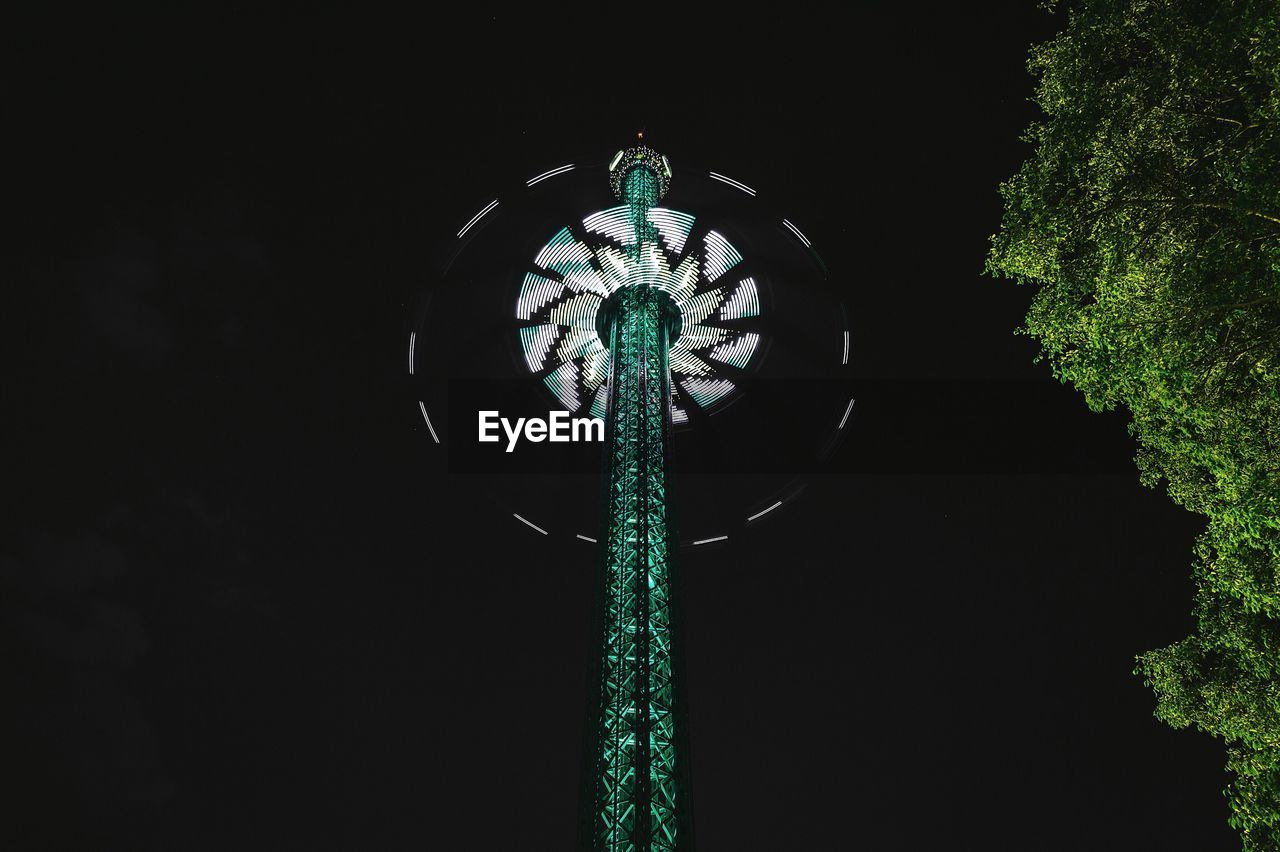 Low angle view of illuminated chain swing ride at prater during night