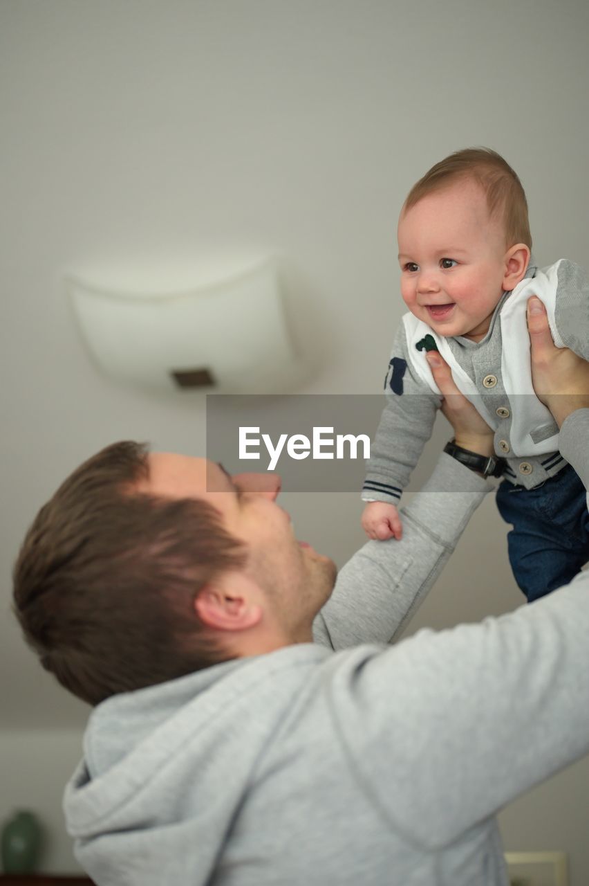 Father holding his baby in air while playing at home