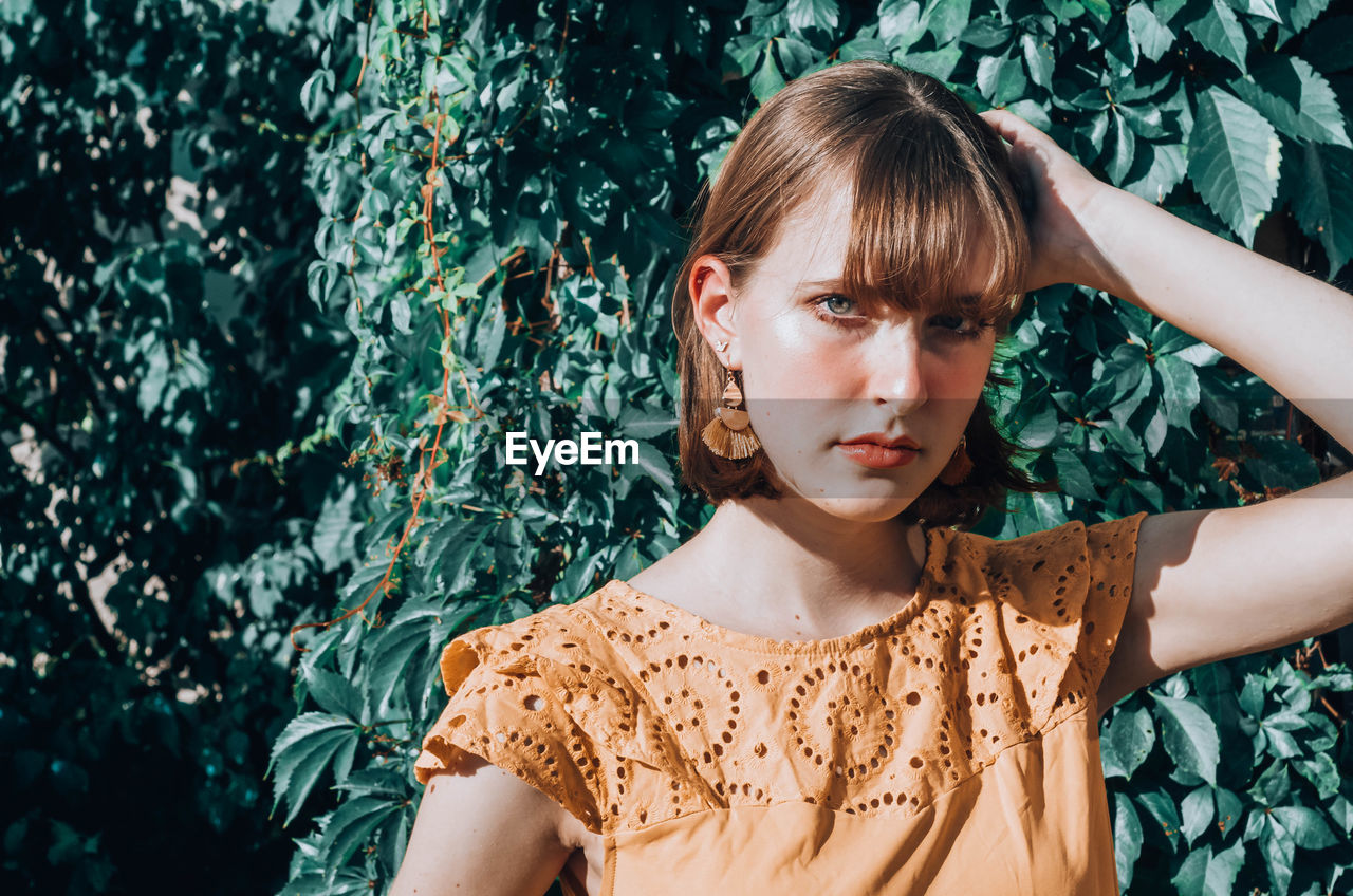 PORTRAIT OF BEAUTIFUL WOMAN AGAINST PLANTS AGAINST BLUE SKY