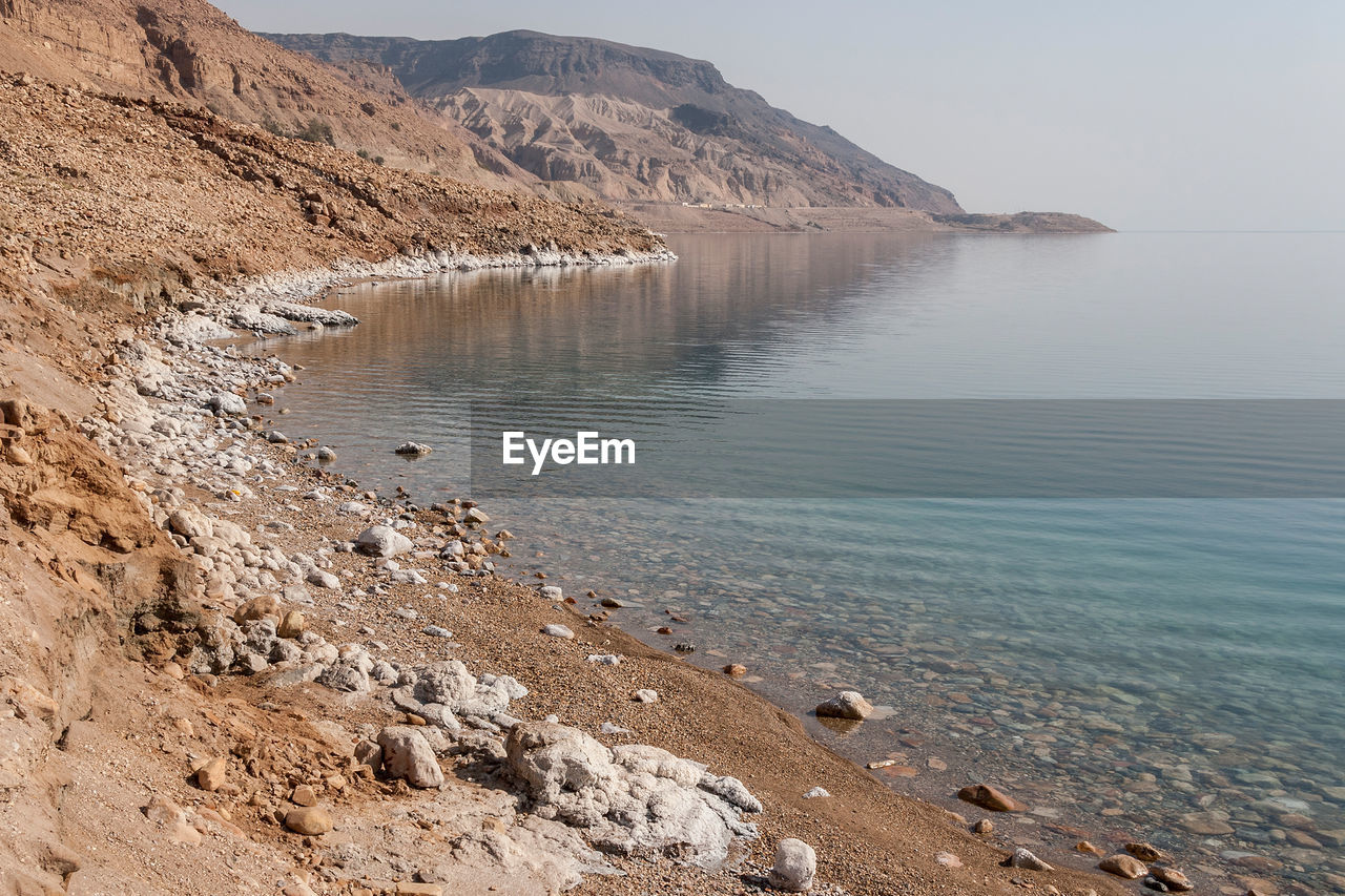 SCENIC VIEW OF SEA AGAINST MOUNTAIN