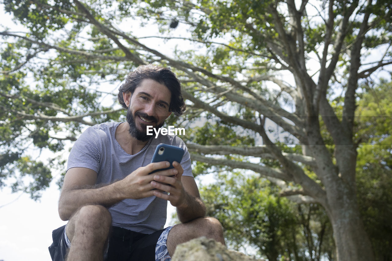 Young man at a park on a beautiful sunny day with mobile phone. home office. green and nature l