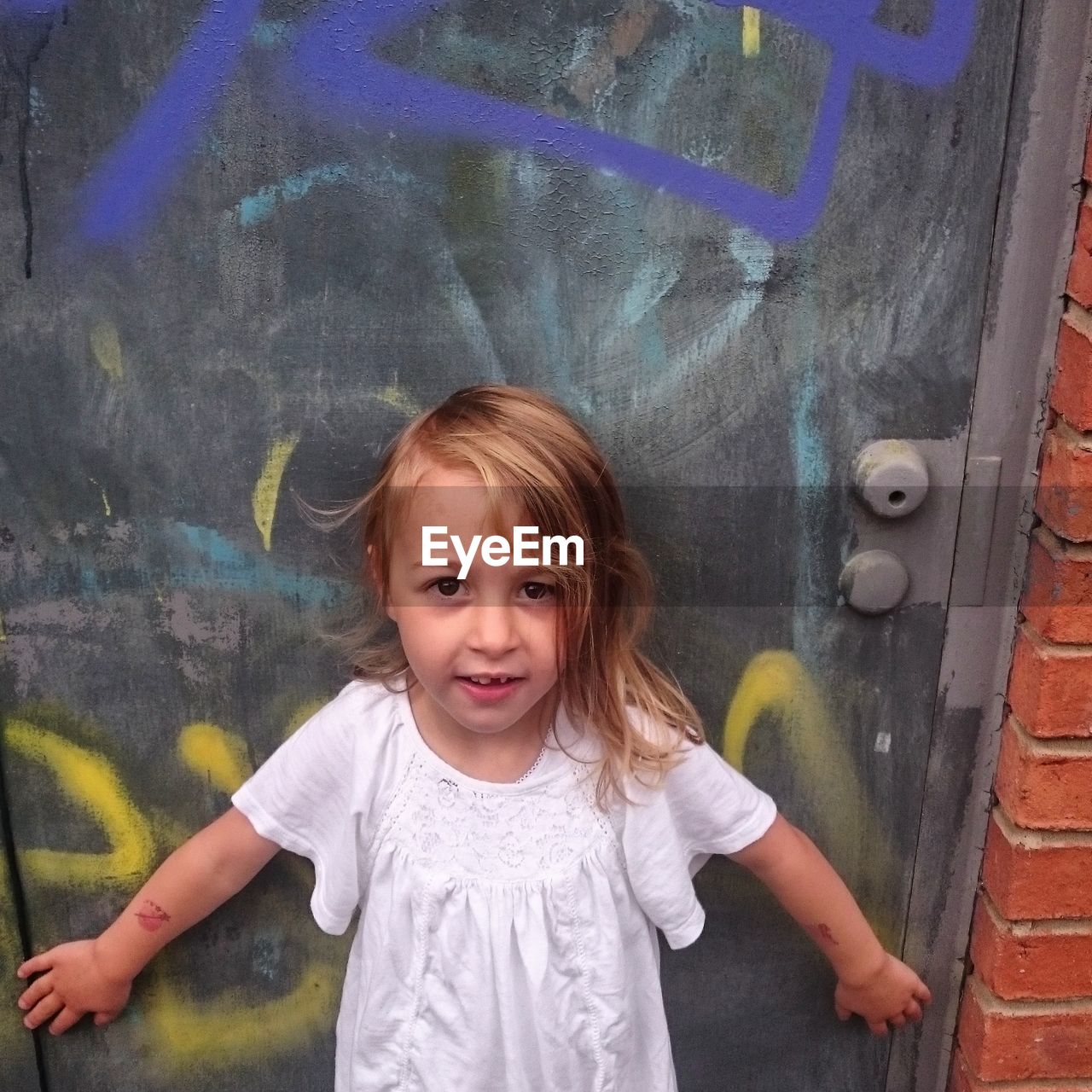 High angle portrait of girl standing against graffiti door